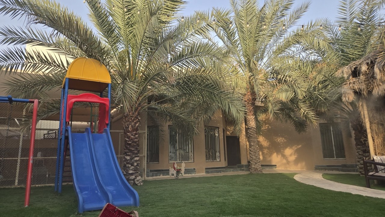 حوش النساء ليلاً مع ألعاب الأطفال والنخيل في استراحة اللؤلؤة